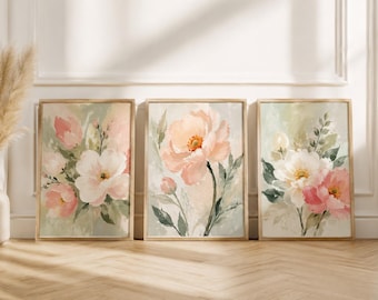 May include: A set of three framed wall art prints featuring watercolor-style floral arrangements in soft shades of pink, white, and sage green. Each rectangular print displays blooming flowers and foliage against a muted, neutral background.