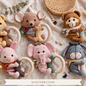 Peut inclure: Six hochets en crochet représentant Winnie l'ourson, une souris, un tigre, Porcinet, un éléphant et Bourriquet, chacun tenant un anneau en bois lisse. Les personnages sont colorés avec des clochettes. Le texte MASTERBLOOM est centré en bas.