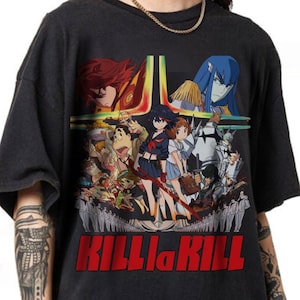 May include: A black short-sleeve t-shirt featuring a large, colorful graphic print of various anime characters from Kill la Kill. The design includes a central figure holding a red blade, surrounded by an ensemble cast, with the text KILL la KILL in red.