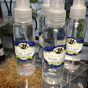 Pode incluir: Quatro garrafas de vidro transparente com pulverizadores cheias de um l&iacute;quido transparente. As garrafas t&ecirc;m r&oacute;tulos com o texto "Lady of the Moss White Light aura & room cleanse".