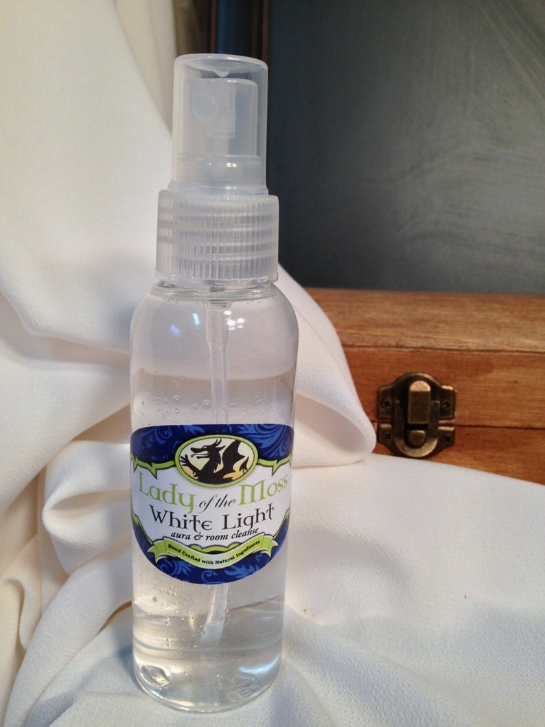 Pode incluir: Uma garrafa de vidro transparente com um bico de pulveriza&ccedil;&atilde;o e um r&oacute;tulo azul e verde que diz "Lady of the Moss White Light aura & room cleanser". Feito &agrave; m&atilde;o com ingredientes naturais.