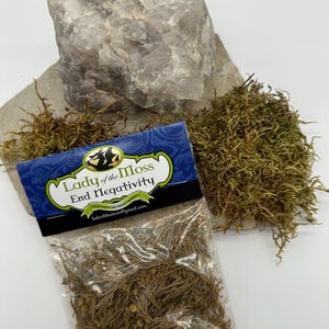 Puede incluir: Una peque&ntilde;a bolsa de pl&aacute;stico transparente llena de hierbas marrones secas y etiquetada "Lady of the Moss End Negativity Hand Crafted and Blessed Herbs ladyofthemoss@gmail.com"
