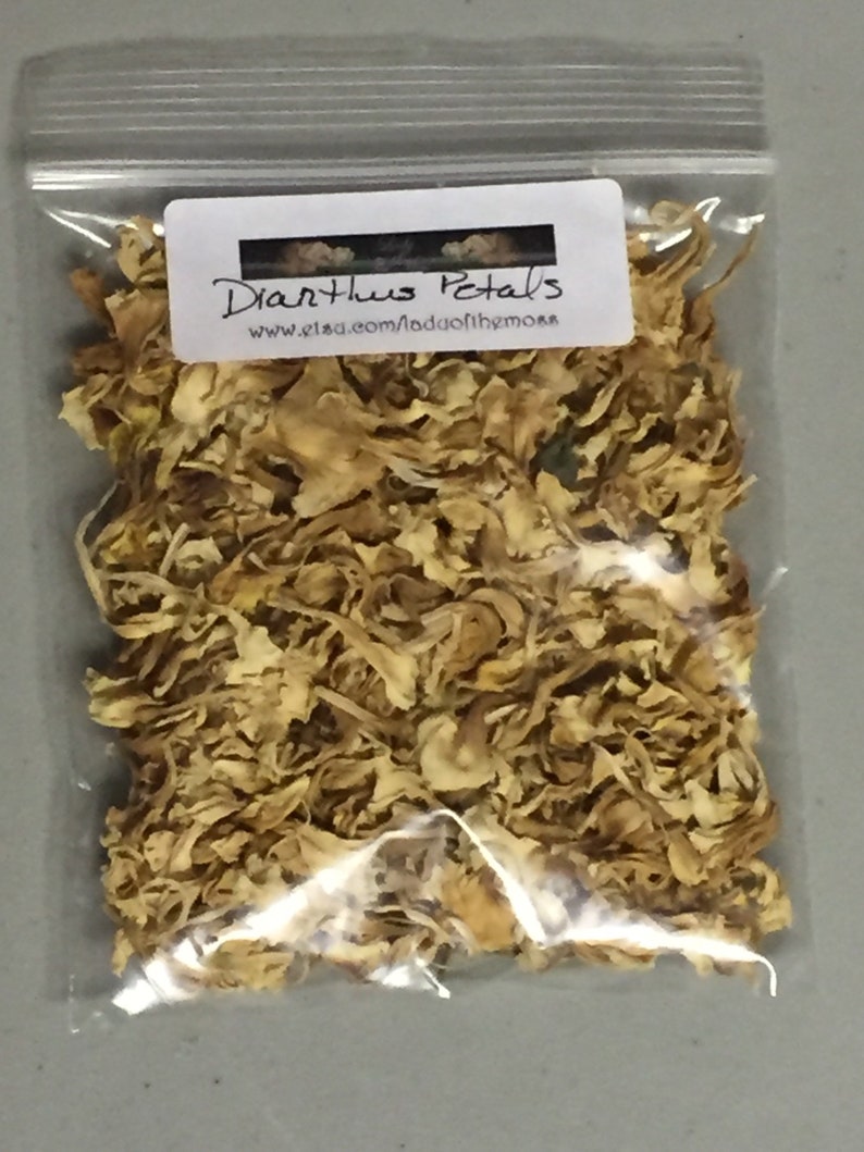 May include: A clear plastic bag filled with dried, light brown Dianthus petals. The bag has a white label with the text "Dianthus Petals" and the website address "www.etsy.com/shop/Madofthemors".