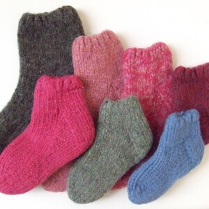 May include: A collection of six knitted wool socks in various colors, including gray, pink, red, and blue. The socks are all different lengths and styles.