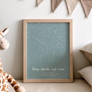 Peut inclure: Un cadre en bois clair encadre une affiche bleu clair représentant une carte du ciel étoilé. Le texte "Une étoile est née" et d'autres informations sont imprimés. Un jouet girafe et des coussins sont visibles au premier plan.