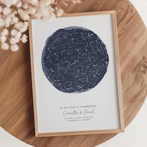 Può includere: Una stampa incorniciata con un cerchio acquerellato blu scuro raffigurante costellazioni. La stampa include il testo "LÀ OÙ TOUT A COMMENCÉ" e i nomi "Camille & Paul", più una data e un luogo. La cornice è in legno chiaro.