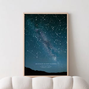 Op de afbeelding: Ingelijste print met een donkerblauwe nachthemel vol witte sterren en sterrenbeelden. De Melkweg is zichtbaar. De tekst "LES &Eacute;TOILES SE SONT ALIGN&Eacute;ES" staat onderaan, samen met namen en co&ouml;rdinaten. De lijst is licht van hout.