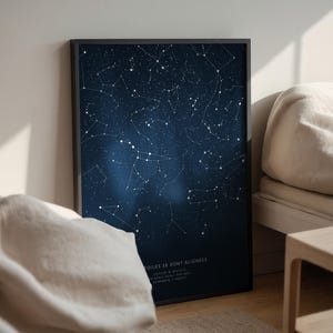 May include: A framed print featuring a dark blue night sky filled with white constellations. The print includes the text "TOILES SE SONT ALIGNEES" and coordinates. The artwork is displayed on a wall next to a bed.