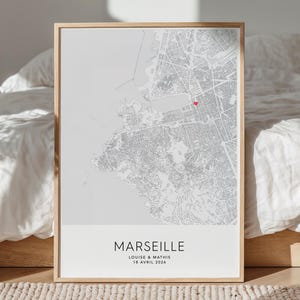 Peut inclure: Impression encadrée d'une carte de Marseille, en nuances de gris, avec un marqueur rouge. L'impression comprend le nom de la ville, et les noms "Louise & Mathis" avec la date "18 Avril 2026". Le cadre est de couleur marron clair.