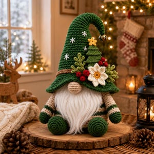 Könnte beinhalten: Eine gehäkelte Wichtelfigur mit einer hohen grünen Mütze, die mit weißen gestickten Schneeflocken, einem kleinen gelben Stern, einem grünen Tannenbaum, roten Beeren und einer weißen Blume verziert ist. Der Wichtel hat eine beige Nase, einen langen weißen Bart und gestreifte Arme.