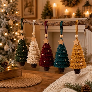 May include: Five crocheted Christmas tree ornaments in dark green, cream, burgundy, teal, and mustard yellow. Each cone-shaped tree features a small wooden star at the top, a round wooden bead on the hanging loop, and tiny metallic beads.