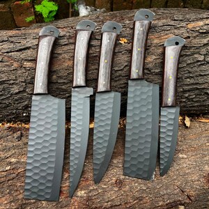 Könnte beinhalten: Ein Set aus fünf Messern mit Griffen aus dunklem Holz und mattschwarzen Klingen mit einer strukturierten Wabenoptik. Jedes Messer hat eine eigene Klingenform, darunter Hack- und Allzweckmesser, mit sichtbaren Nieten an den Griffen.