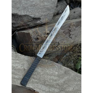 May include: A single-edged sword featuring a silver-coloured metal blade with an intricate, etched filigree pattern running along its length. The handle is wrapped in a textured black material, providing a secure grip for the user. The blade is straight.