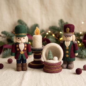 Peut inclure: Deux figurines de casse-noisette en laine feutrée, une bougie feutrée dans un bougeoir et une petite boule à neige en feutre contenant un arbre miniature et une boule de neige. Les casse-noisettes portent des uniformes vert et bordeaux.