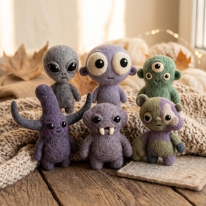 Könnte beinhalten: Eine Sammlung von sechs kleinen, nadelgefilzten Kreaturen in verschiedenen Formen und Farben. Die Gruppe umfasst einen grauen Alien, eine violette Figur mit großen Augen, ein grünes dreiäugiges Monster, eine violette Figur mit Hörnern und ein graues Wesen.