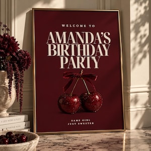 May include: A rectangular framed poster with a deep burgundy background. The text reads WELCOME TO AMANDA'S BIRTHDAY PARTY and SAME GIRL JUST SWEETER. Below the main text, two dark red cherries are tied together with a thin velvet ribbon.