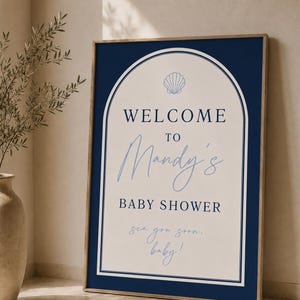 May include: A rectangular sign with a dark navy blue border and an arched cream center. It features the text "WELCOME TO Mandy's BABY SHOWER" in navy blue, with "sea you soon, baby!" in light blue script, and a small light blue seashell icon.