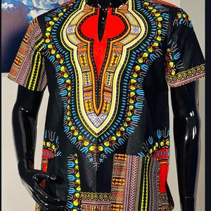 May include: A short-sleeved shirt featuring a black base with a vibrant, multi-colored dashiki-inspired pattern. The design includes a prominent red central panel at the neckline, surrounded by intricate yellow, blue, and white geometric motifs.