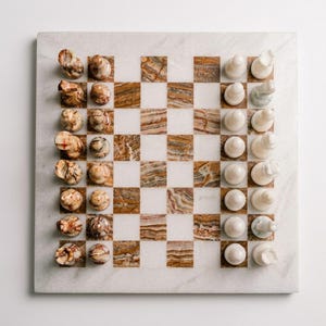 May include: A square chess board made of polished stone with alternating white and brown marbled squares. The board features a set of carved stone chess pieces, with one side displaying brown and white marbled patterns and the other side in solid white.