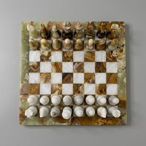 May include: A square chess set crafted from polished stone featuring a board with alternating white and brown marbled squares. The border is a translucent green stone. The chess pieces are carved from matching brown and white stone materials.