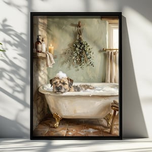 May include: A framed wall art print depicting a small brown dog with a bubble on its head relaxing in a white clawfoot bathtub. The bathroom scene includes a stone wall, a hanging bundle of dried eucalyptus, toiletries, and a lit candle.