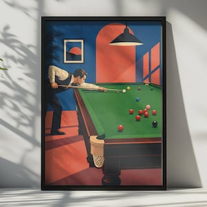 May include: A framed art print depicting a person in a vest and dress shirt playing billiards on a green table. The scene features a blue wall, a red arched doorway, a hanging lamp, and various colored billiard balls scattered across the felt surface.