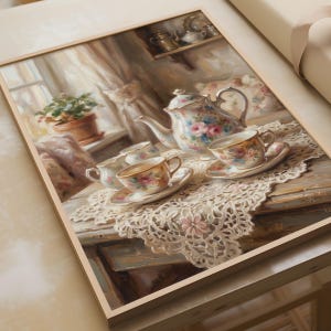 Op de afbeelding: Een ingelijst schilderij met een bloemrijke porseleinen theepot en twee bijpassende theekopjes op schoteltjes, rustend op een wit kanten kleedje. De scène bevat een klein melkkannetje, een plant in een pot en een plank met metalen servies.