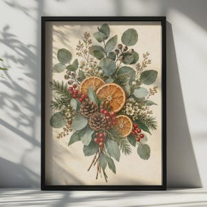 May include: A framed wall art print featuring a botanical arrangement of eucalyptus leaves, pine needles, pinecones, small white flowers, red berries, and three dried orange slices, all set against a light cream-colored background.