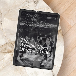 May include: A digital tablet displaying a black and white guide titled The Wedding Guest Dresscode Guide by Dearly Planned & Co. The screen shows a photograph of people holding sparklers at an evening event with text explaining dress codes.
