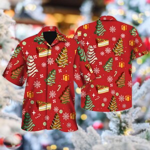 Puede incluir: Una camisa de manga corta con botones en color rojo que presenta un patrón repetitivo de árboles de Navidad, cajas de regalo, trozos de pastel y copos de nieve blancos. La camisa tiene un cuello clásico y cierre frontal de botones.