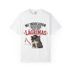 May include: A white t-shirt featuring a graphic of a crying grey tabby cat wearing a black cap. The text reads MI INDICADOR FAVORITO SON MIS LÁGRIMAS in black and red. To the left of the cat is a downward-trending stock market candlestick chart.