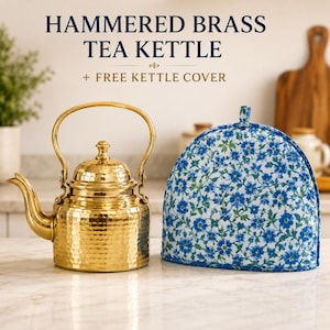May include: A hammered brass tea kettle with a curved handle and spout, accompanied by a fabric tea kettle cover featuring a blue and green floral pattern. The text HAMMERED BRASS TEA KETTLE + FREE KETTLE COVER is visible above the items.