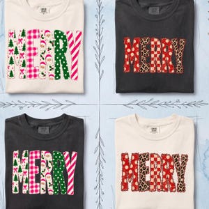 Puede incluir: Cuatro camisetas de manga corta en color crema y negro. Dos camisetas presentan la palabra MERRY con patrones de árboles de Navidad, cuadros rosas, caras de Papá Noel, puntos verdes y rayas. Otras dos muestran MERRY en rojo, leopardo y cuadros.