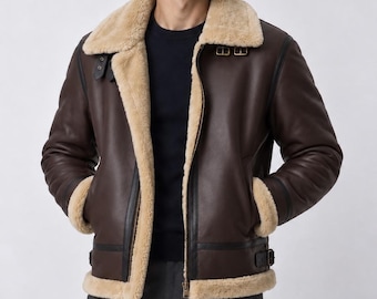 Puede incluir: Una chaqueta de cuero marrón oscuro con un grueso forro de borrego beige, un cuello ancho doblado, cierre de cremallera frontal y correas con hebilla ajustables en el cuello y la cintura. La chaqueta tiene mangas largas con puños de borrego.
