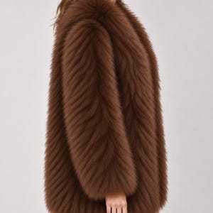 May include: A long-sleeved, hip-length coat made of thick, textured brown faux fur. The garment features a high, plush collar and a dense, shaggy pile that covers the entire exterior surface, providing a uniform, voluminous appearance throughout.