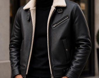 Puede incluir: Una chaqueta de cuero negro con cuello y forro interior de piel sintética de color crema. La chaqueta incluye un cierre de cremallera metálico plateado, un bolsillo diagonal con cremallera en el pecho y correas con hebillas ajustables.