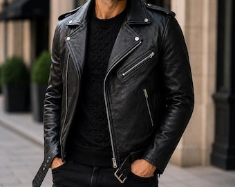 Puede incluir: Una chaqueta de cuero negra para motocicleta con cuello ancho de muesca, cremalleras de metal plateado, detalles de botones a presión en las solapas y un cinturón ajustable en la cintura con hebilla. Se lleva sobre un suéter de punto negro.