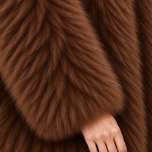 May include: A long-sleeved garment made of thick, plush, brown faux fur. The material features a dense, shaggy texture with long, soft fibers that create a layered, voluminous appearance across the entire surface of the fabric, showing a deep brown tone.