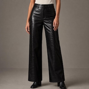 Puede incluir: Pantalones negros de talle alto con una textura brillante en relieve de piel de cocodrilo. Estos pantalones presentan una silueta de pierna ancha, una cintura estructurada con trabillas, cierre frontal de botón y cremallera, y dos bolsillos.