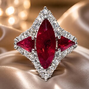 Può includere: Un anello color argento con una grande pietra preziosa rosso scuro taglio marquise al centro, affiancata da due pietre rosse triangolari. L'intera composizione è circondata da un alone di piccole pietre bianche rotonde e trasparenti.