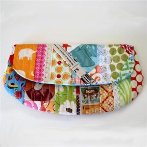 May include: A colorful patchwork fabric clutch purse with a variety of patterns, including polka dots, stripes, and floral designs. The purse is made from a variety of fabrics, including cotton, lace, and newspaper.