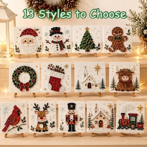 May include: Thirteen square white canvases on miniature wooden easels, each featuring a textured Christmas-themed design made of small beads. Designs include Santa, a snowman, a tree, a gingerbread man, a wreath, a stocking, a church, and a train.