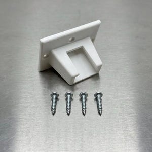 May include: A white plastic mounting bracket featuring a rectangular base with two pre-drilled screw holes and a central U-shaped channel. The bracket is accompanied by four silver-colored metal screws with threaded shanks and flat heads.
