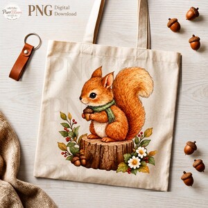 May include: A beige canvas tote bag featuring a printed illustration of a brown squirrel wearing a green scarf, sitting on a tree stump while holding an acorn. The design includes surrounding autumn leaves, red berries, and white flowers.