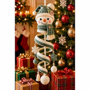 Pode incluir: Um enfeite de boneco de neve em crochê com um gorro verde com pompom branco, um cachecol verde com botão de madeira e um corpo longo em espiral nas cores verde e branco. O enfeite inclui flocos de neve e pequenas esferas penduradas.