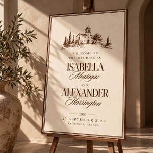 May include: A rectangular wedding welcome sign on a wooden easel featuring a dark brown ink illustration of a villa at the top. The text reads: WELCOME TO THE WEDDING OF ISABELLA Montague AND ALEXANDER Harrington 25 SEPTEMBER 2025 PROVENCE, FRANCE.