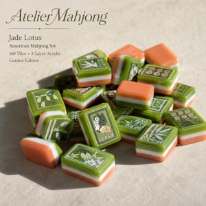 May include: A pile of 160 three-layer acrylic Mahjong tiles from the Atelier Mahjong Jade Lotus Garden Edition. The tiles feature green, white, and orange layers with engraved illustrations of bamboo, lotus, and Joker characters in green ink.