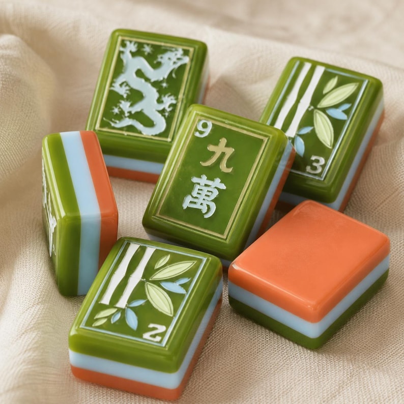 May include: A collection of six rectangular Mahjong tiles featuring green, orange, and light blue layers. The tiles display engraved designs including a white dragon, bamboo stalks, the number 3, the number 2, and the Chinese character for nine.