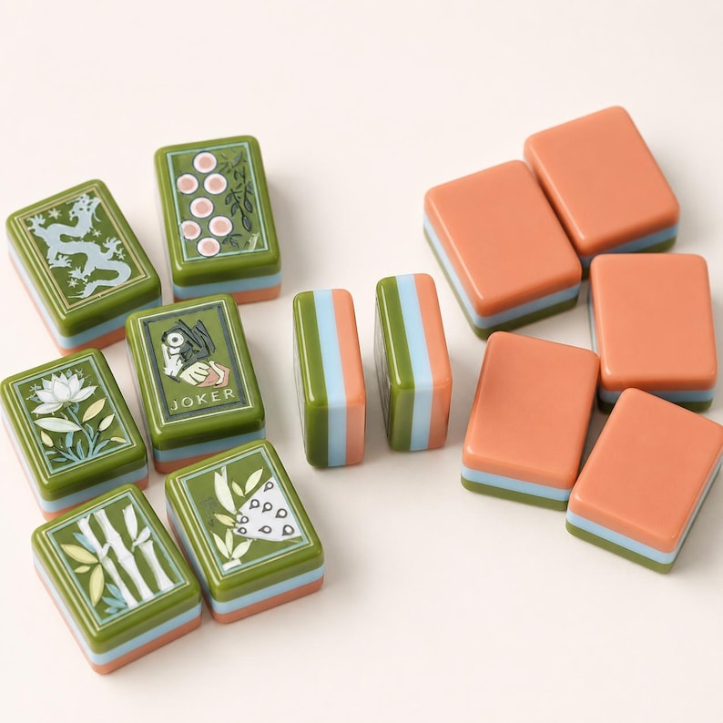 May include: A collection of rectangular mahjong tiles featuring a mix of green tiles with intricate illustrations of dragons, flowers, bamboo, and a Joker card, alongside solid peach-colored tiles. Each tile has a layered blue and peach base.