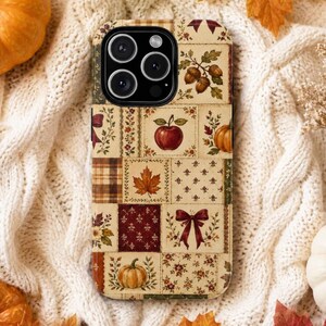 Könnte beinhalten: Eine Smartphone-Hülle mit einem Patchwork-Design aus herbstlichen Illustrationen, darunter rote Äpfel, orangefarbene Kürbisse, braune Eicheln, Ahornblätter und kastanienbraune Schleifen auf einem cremefarbenen Hintergrund.